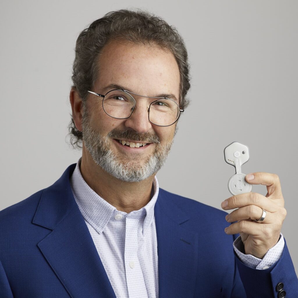El director general de BioIntelliSense, James Mault, posa con el wearable BioSticker de la empresa. Fuente: https://biointellisense.com