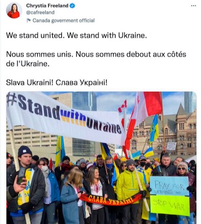 Chrystia Freeland participa en una manifestación de los banderistas de ‎OUN-B contra la intervención rusa en Ucrania. Los colores negro y rojo de la banderola ‎identifican a los banderistas y el eslogan “¡Gloria a Ucrania!” es el grito de guerra de los ‎banderistas.