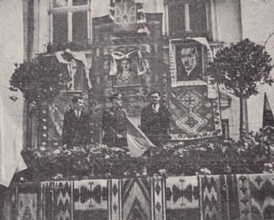 Celebración de la Ucrania “independiente” en presencia de dignatarios ‎nazis. Detrás de los oradores se ven los retratos –de izquierda a derecha– de Stepan Bandera, ‎Adolf Hitler y Yevhen Konovalets.‎